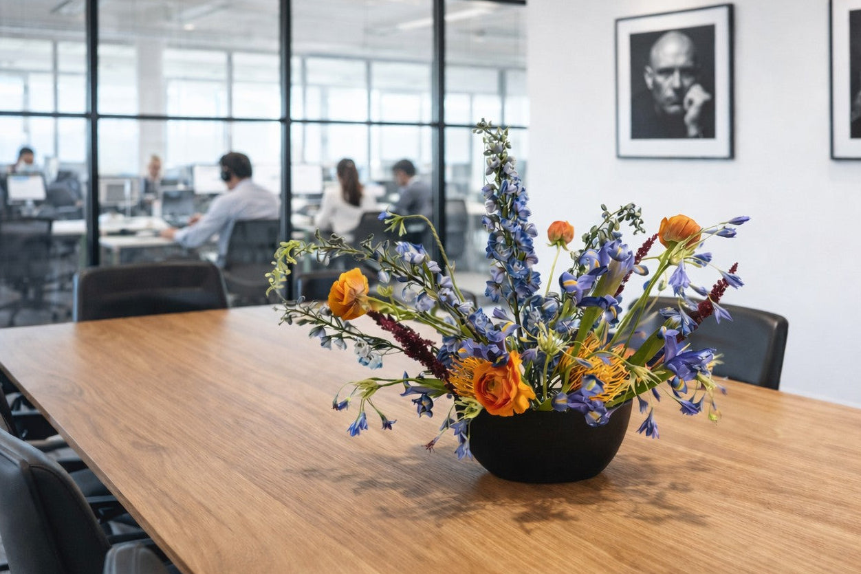 Conference room table with a floral arrangement, chairs, and wall art.